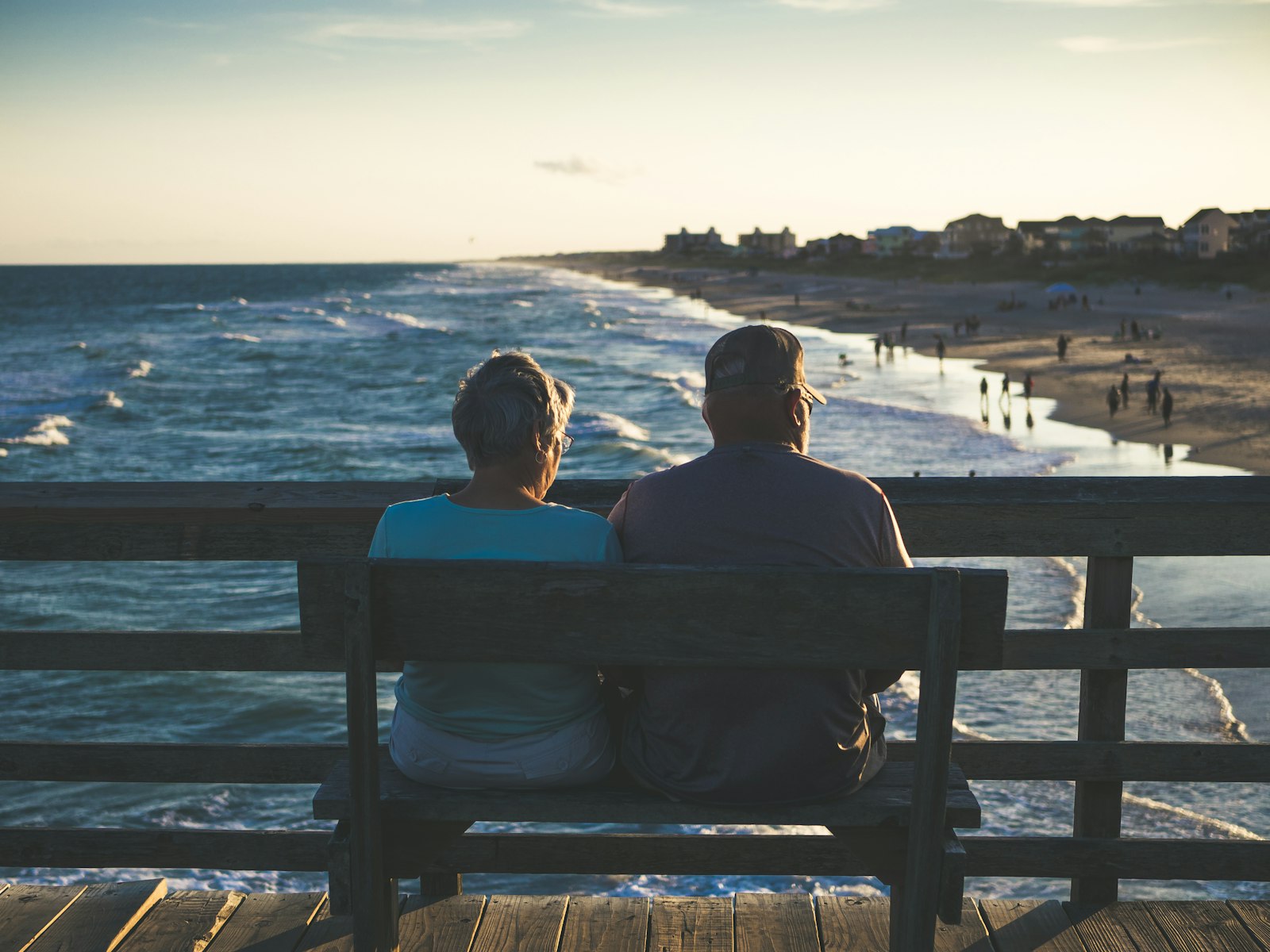 Casal sentado em um banco observando o mar, representando a aposentadoria